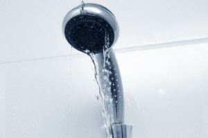 Showerhead dripping water, illustrating potential bathroom leak issues and the need for plumbing maintenance.