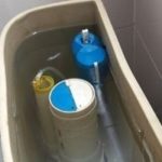 Toilet tank components with float valves and water level, relevant for plumbing and sump pump maintenance at Bud's Plumbing.