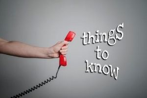 Hand holding a red telephone receiver with the text "things to know" emphasizing important plumbing information for homeowners considering sump pumps.