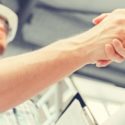 Two individuals shaking hands in a professional setting while discussing plumbing services and repairs.