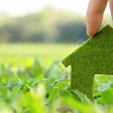 Hand holding a green grass-like house model, symbolizing eco-friendly plumbing solutions by Bud's Plumbing & Repair Service.