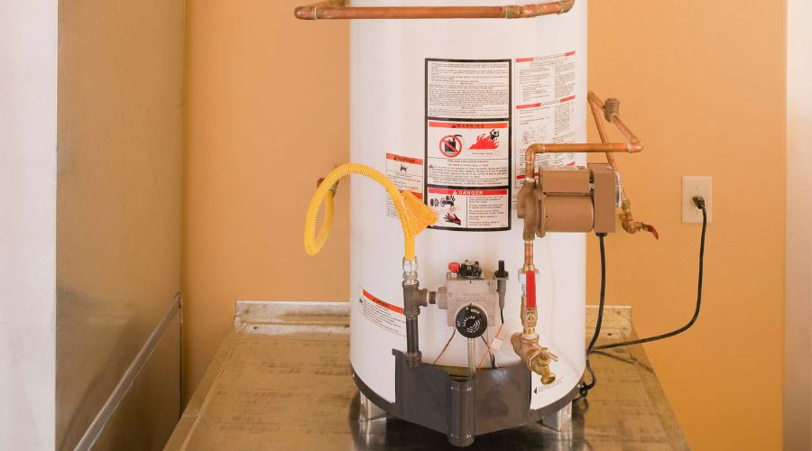Water heater with safety labels, copper pipes, and gas line for plumbing maintenance at Bud's Plumbing & Repair Service.
