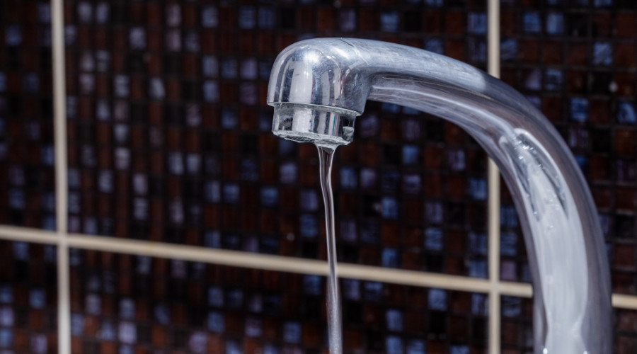 Water faucet with flowing water, highlighting plumbing issues related to low water pressure and fixture performance.